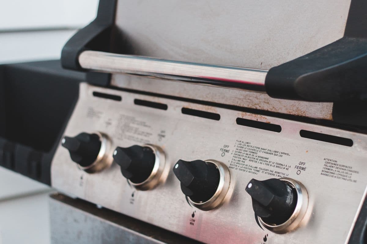 A stainless-steel propane gas grill with control knobs