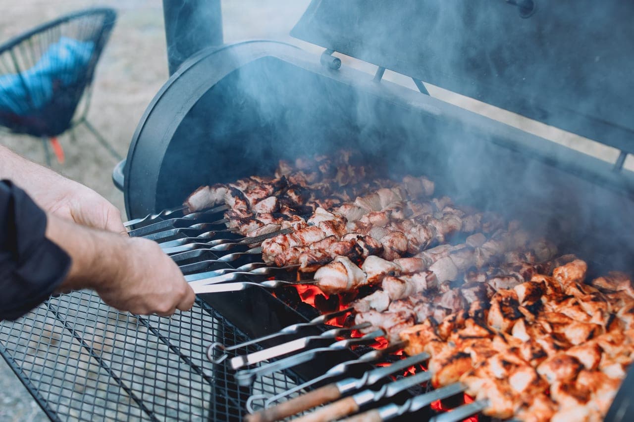 An offset smoker with smoke rising from the chimney